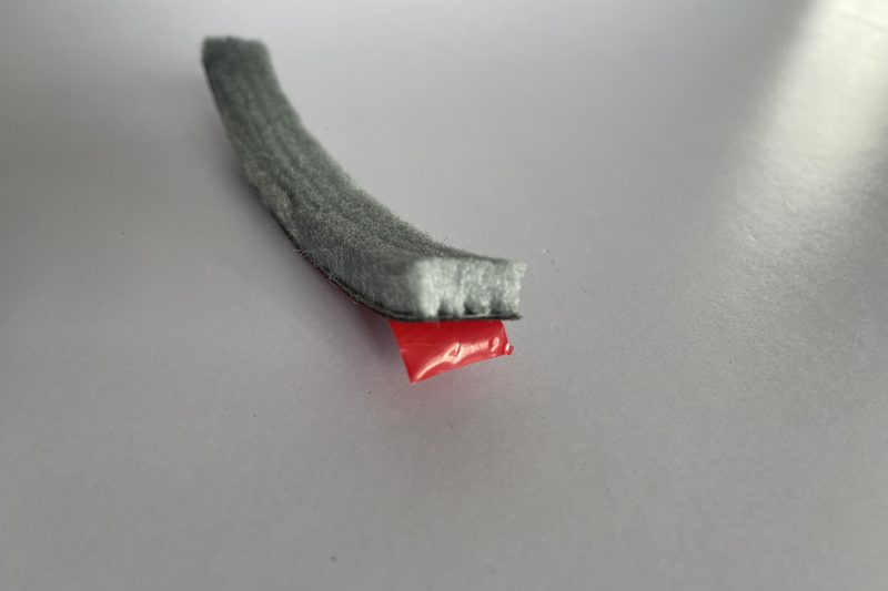 Acrylic transfer adhesive with the red liner peeled back — no foam carrier.