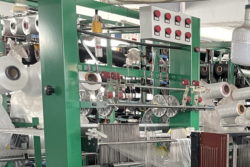Yarn packages and heddles on a braiding loom, feeding filament into the band