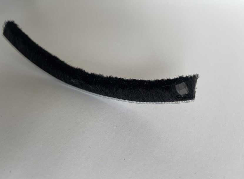 Fin seal weatherstrip with the polypropylene centre fin standing above the pile at the cut end.