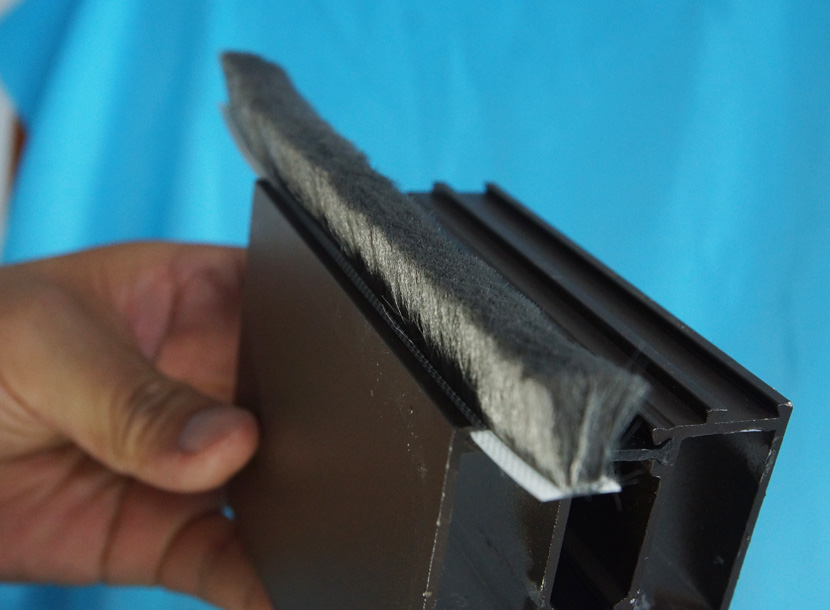 Fin seal weatherstrip seated in the channel of an aluminium extrusion, cut end facing the camera.