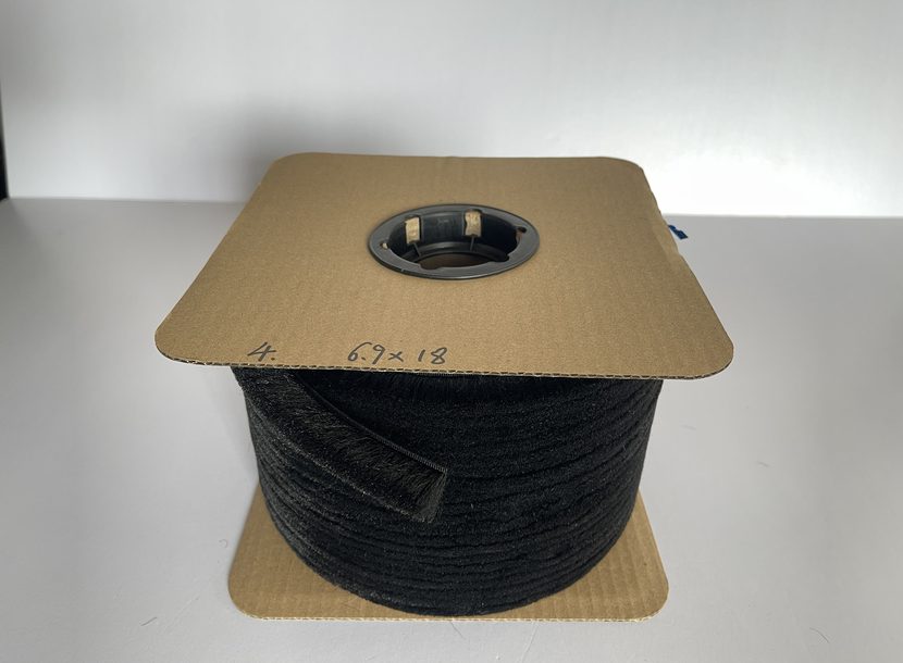 Pile weatherstrip wound on a cardboard-flanged spool, the core visible through the centre.